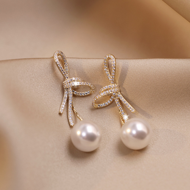 Boucles d'oreilles en perles dorées avec un nœud brillant
