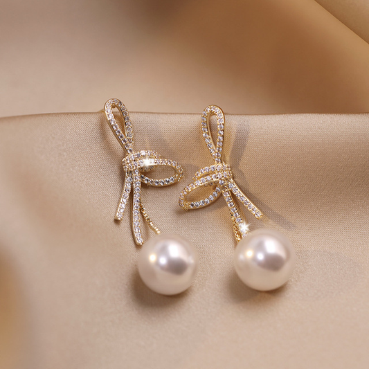 Boucles d'oreilles en perles dorées avec un nœud brillant